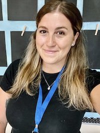 Juliana, wearing a black shirt and smiling in a selfie.