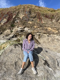 Madeleine sitting on a rock at the beach.